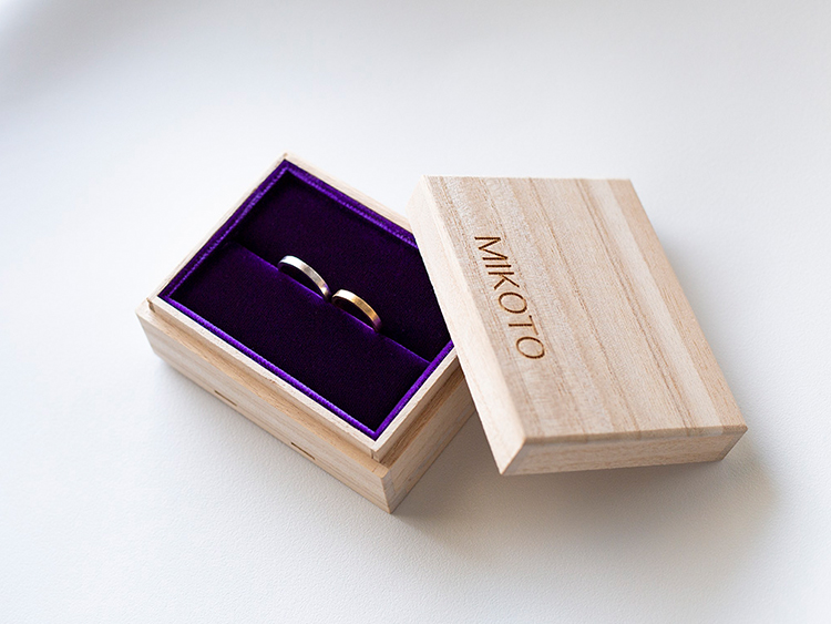鶴のブランドロゴを刻印した木箱に入れた結婚指輪と婚約指輪