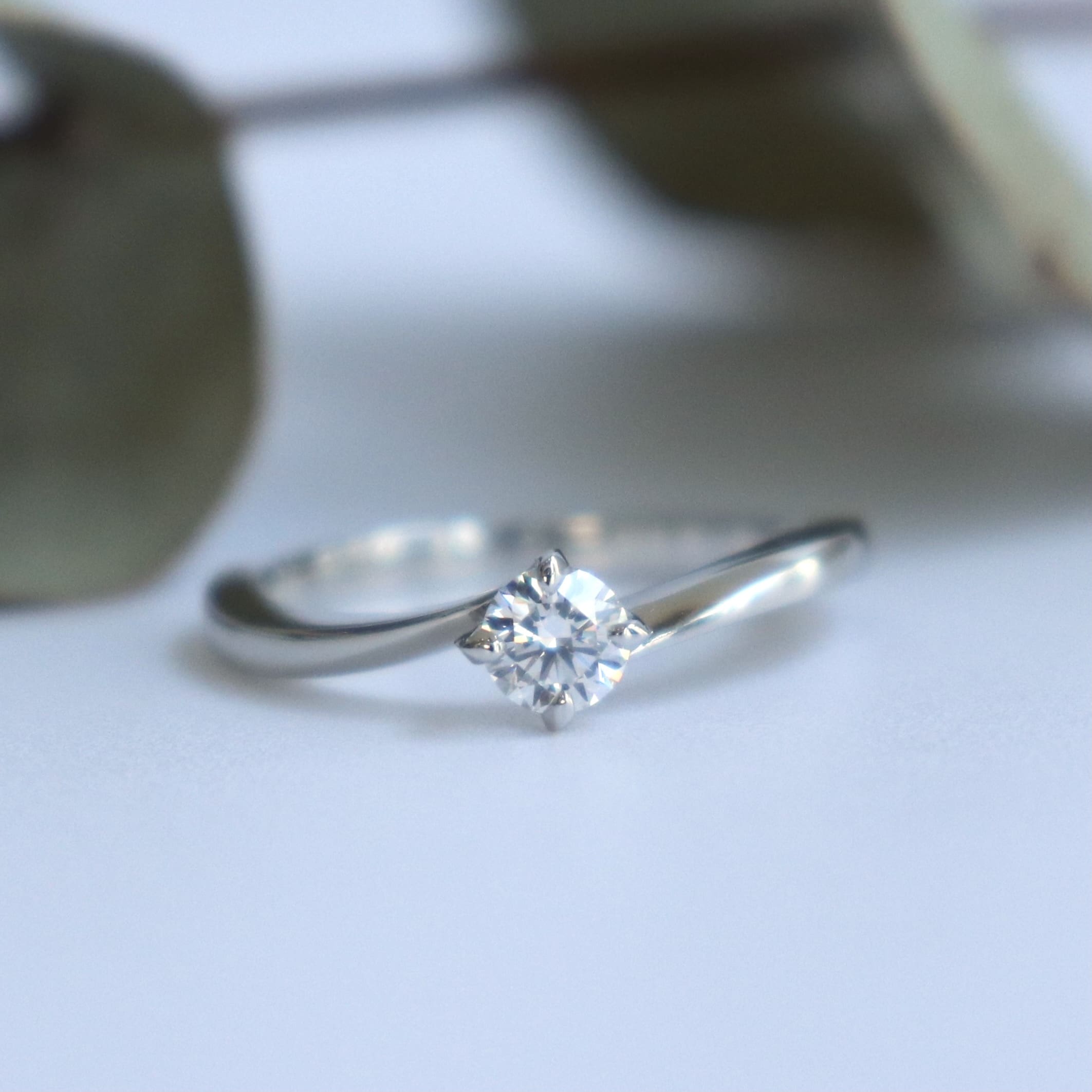 輝くダイヤに向かって伸びるウェーブが美しい婚約指輪