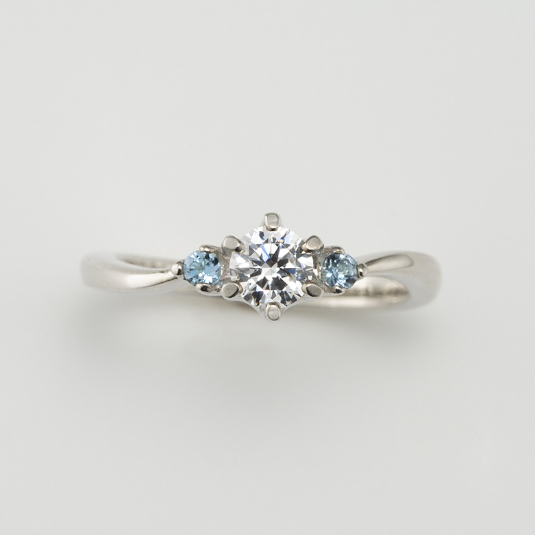アクアマリンをダイヤモンドの両脇に留めた清涼感のある婚約指輪